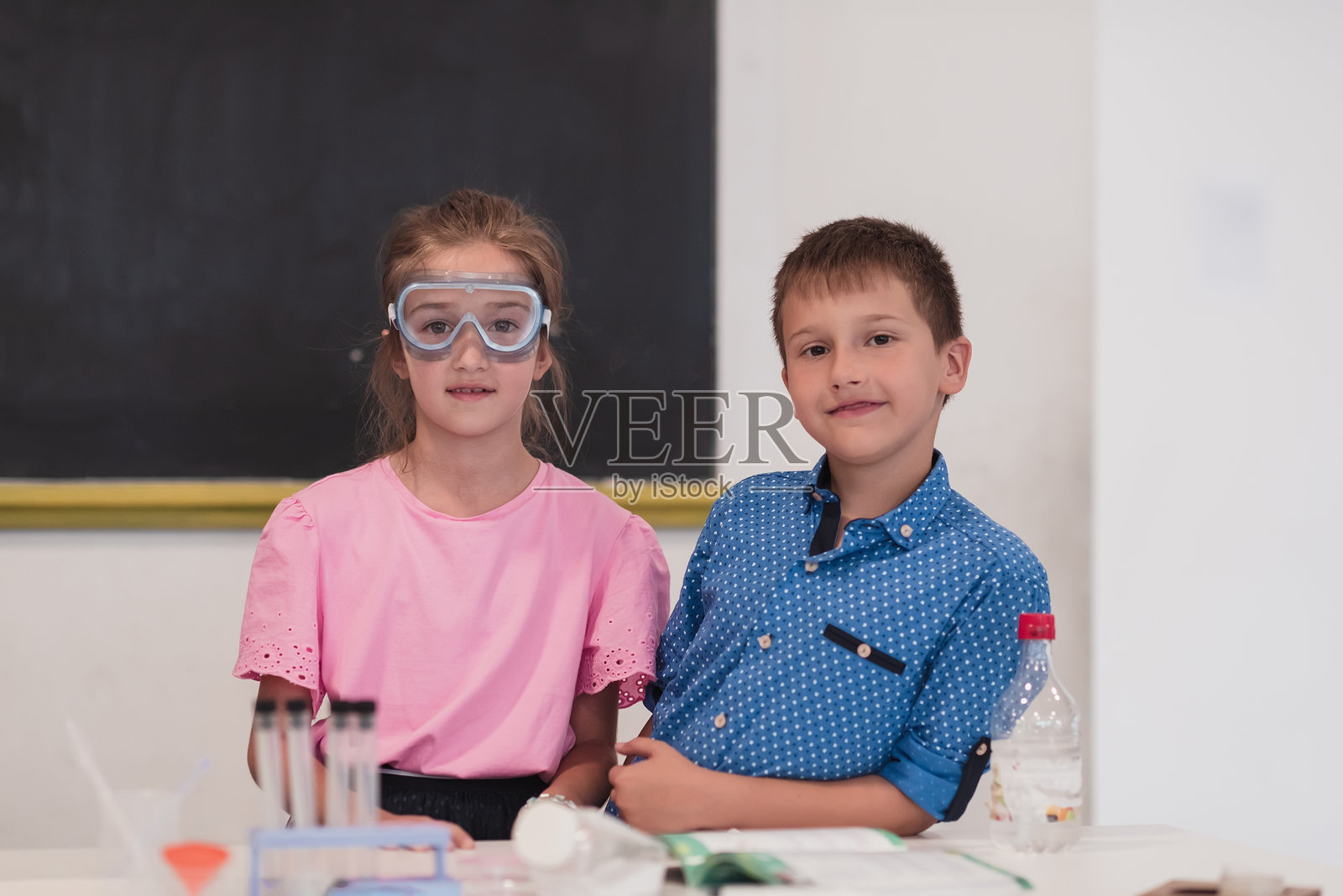 小学科学教室:热情老师向一群多元化的孩子讲解化学知识,一个小男孩在烧杯中混合化学品。孩子们饶有兴趣地学习。照片摄影图片