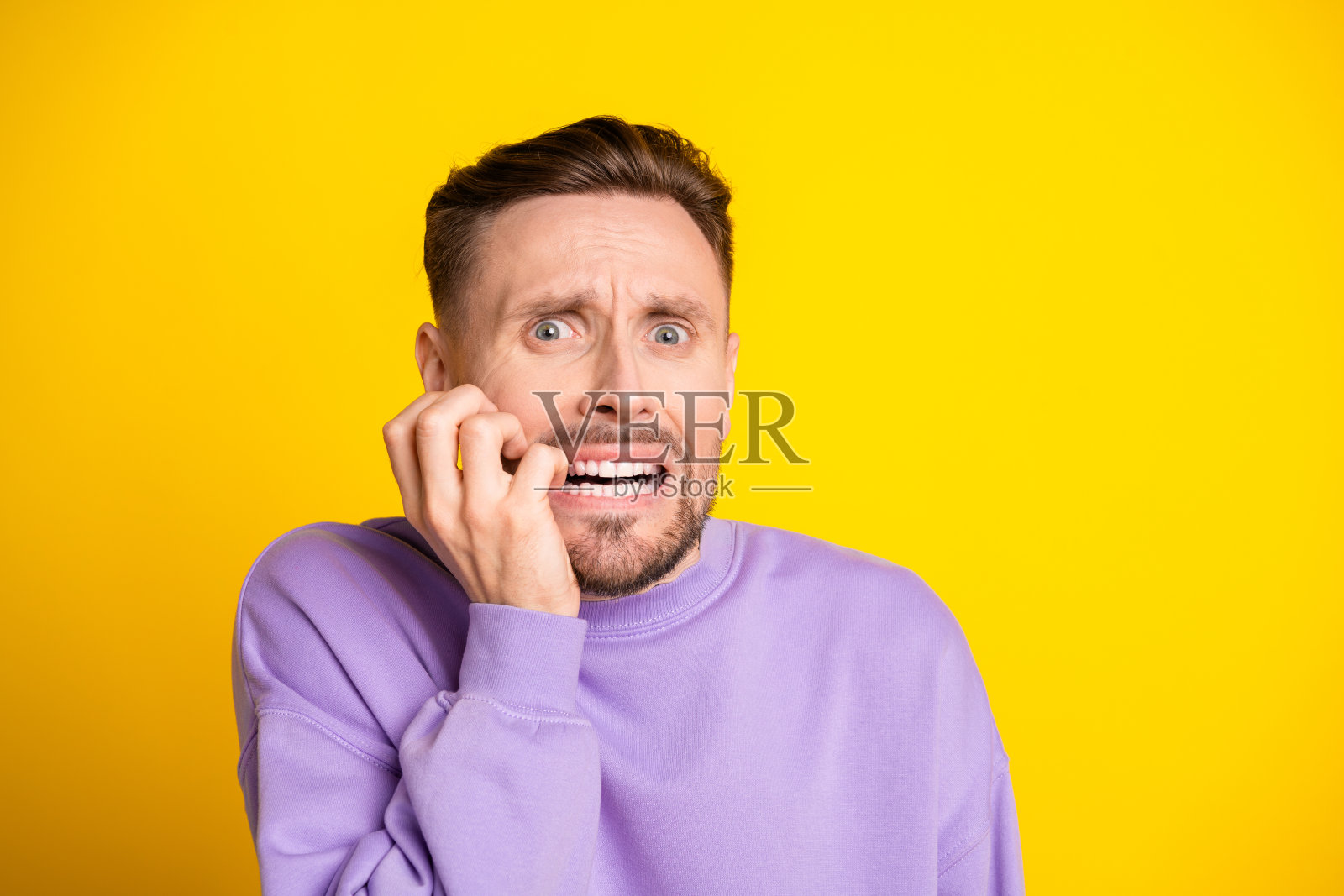 身穿紫色连帽衫的年轻男子,在明亮的黄色背景前,接听电话时显得很惊讶照片摄影图片
