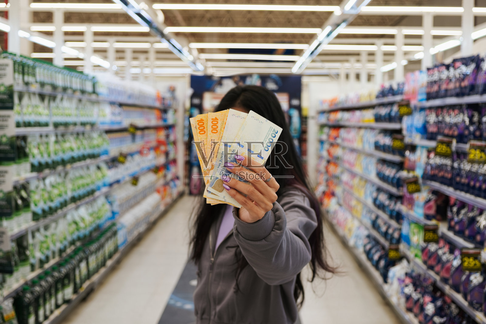 女子在超市里拿着阿根廷比索照片摄影图片