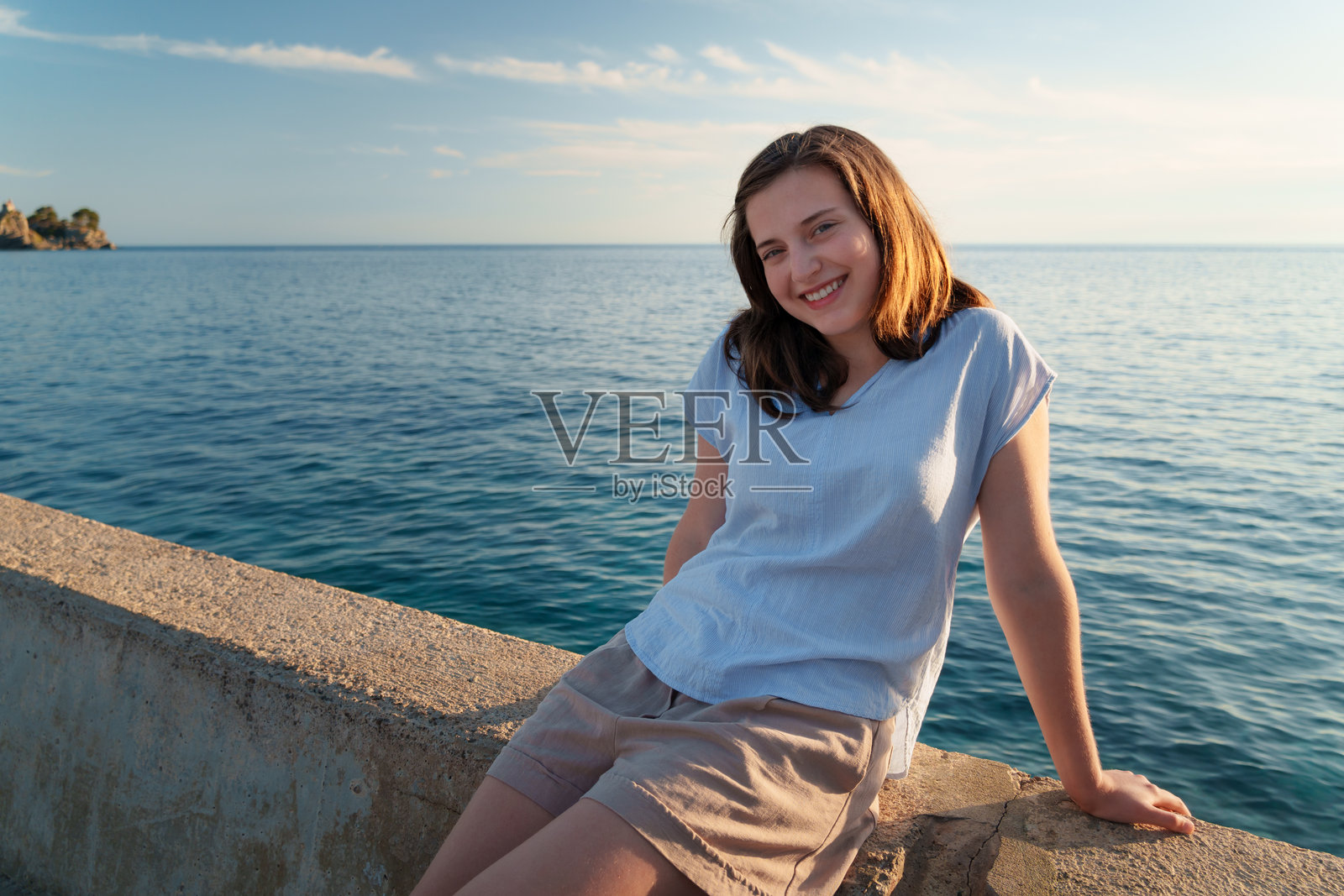 日落时分,在佩特罗瓦茨的码头上,一位面带微笑的年轻女子特写肖像。快乐的情绪,夏日假期海滨度假概念。照片摄影图片