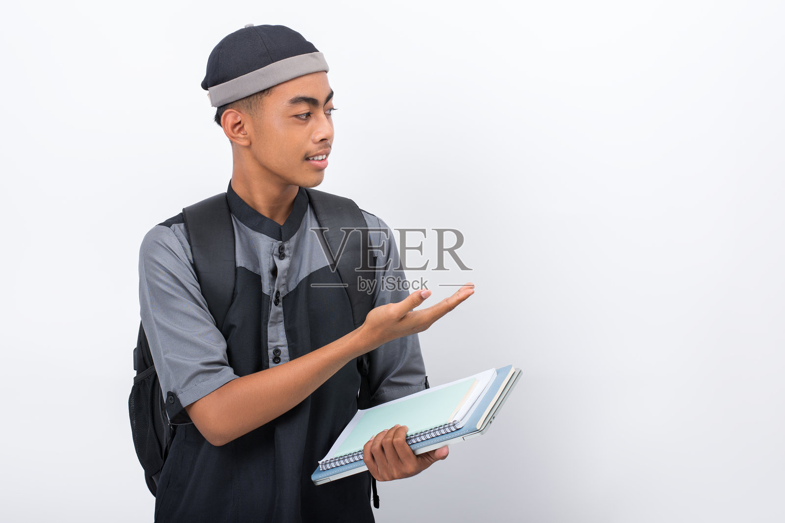 微笑着的马德拉萨学生,在白色背景下展示某物照片摄影图片