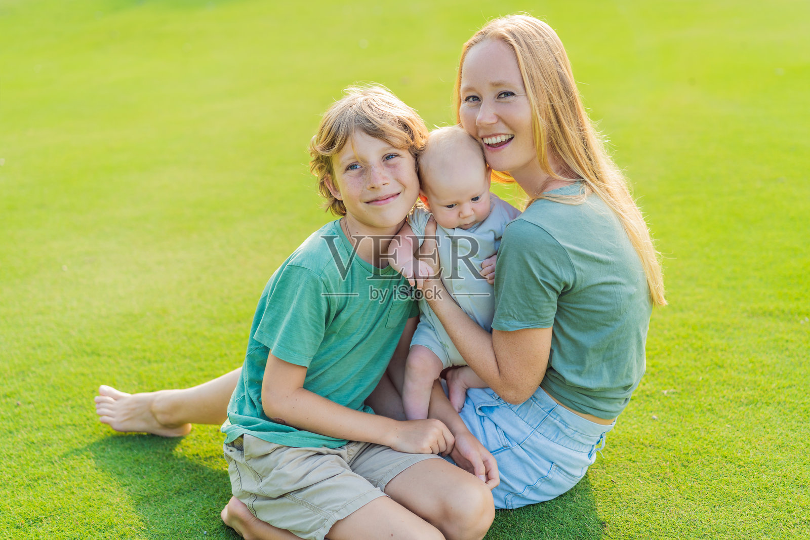 母亲、大儿子和新生儿在公园草地上。一家人在大自然中共享亲子时光。为人父母、爱与家庭纽带的概念照片摄影图片