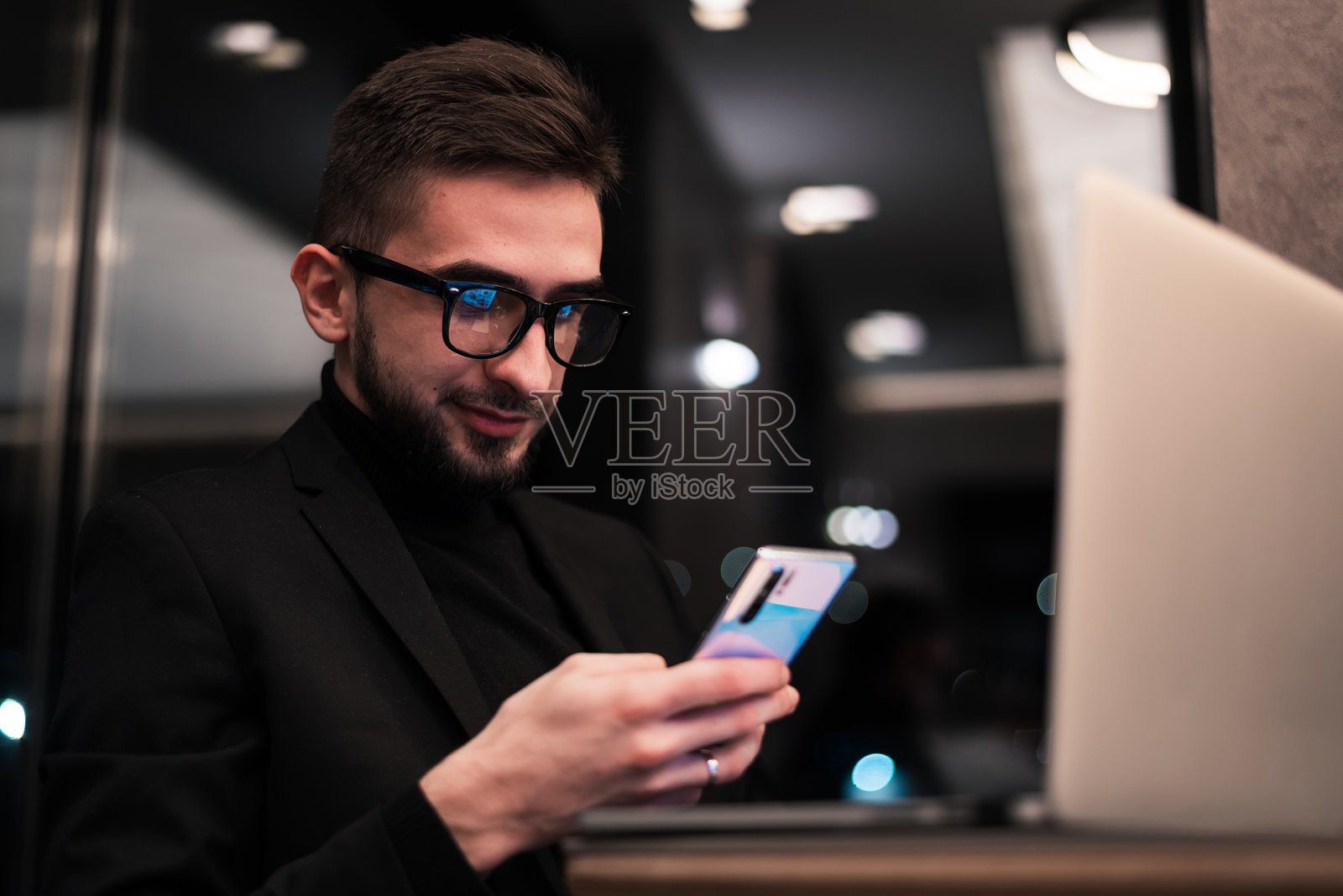 一位年轻的商务男士在办公室使用智能手机工作。照片摄影图片