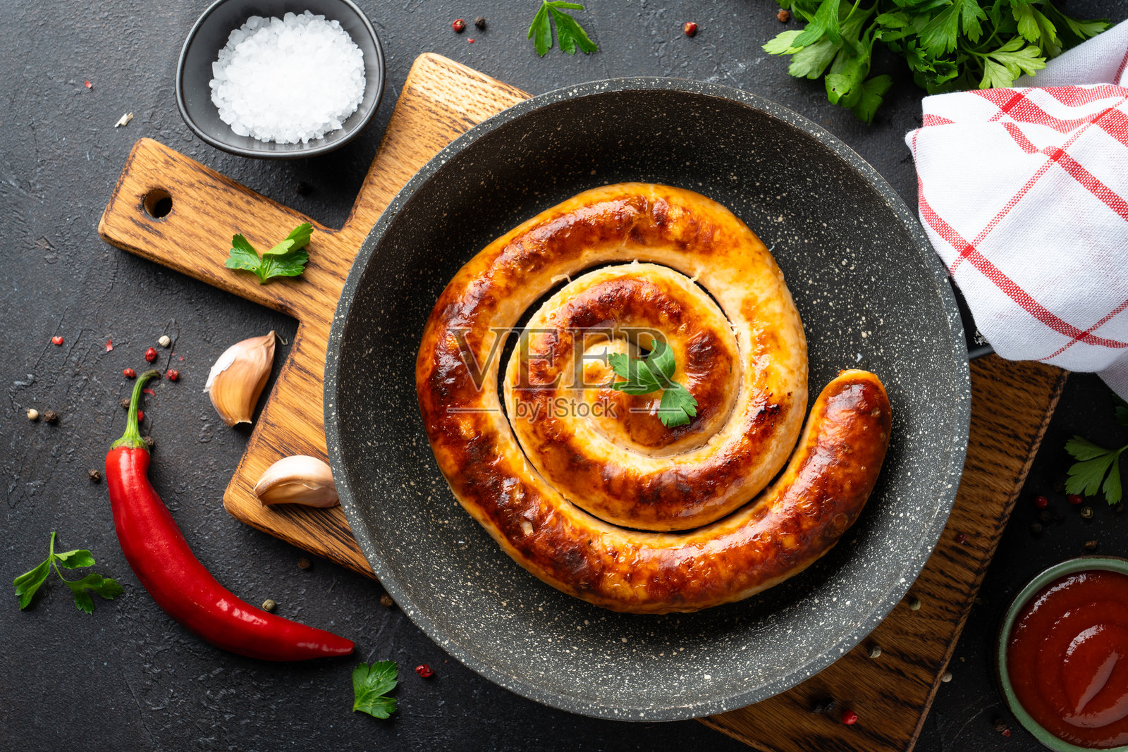 平底锅里烤的德国香肠,深色厨房桌子俯视图。照片摄影图片