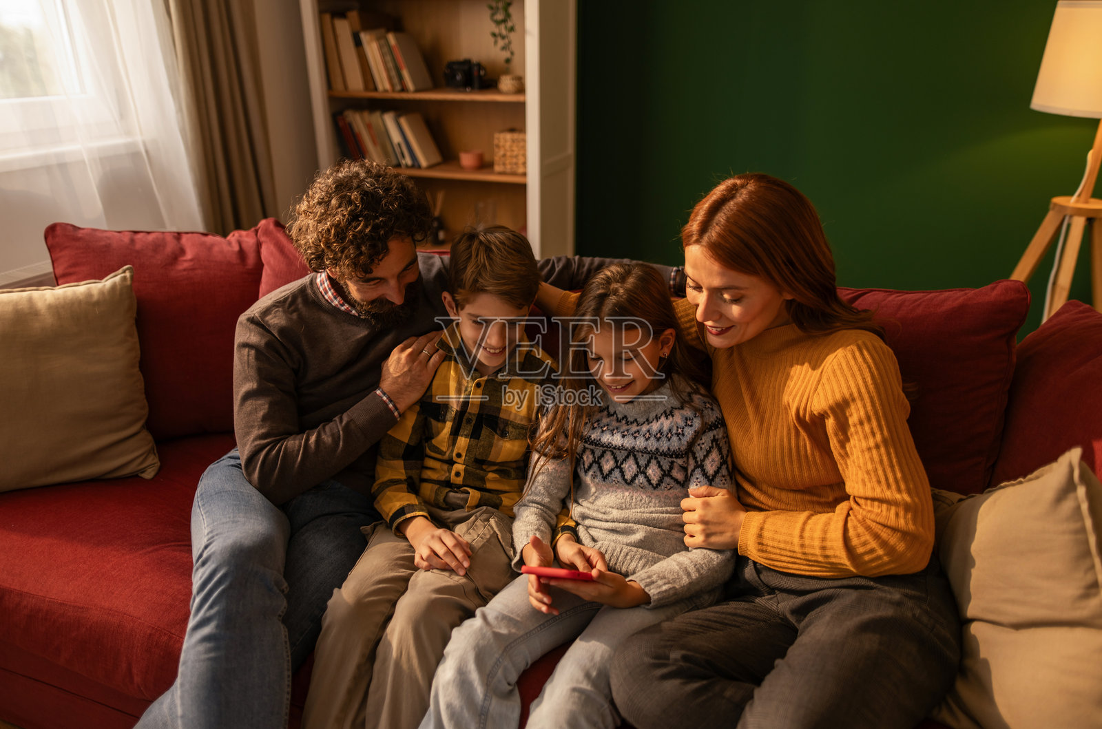 一家人开心地在沙发上一起看手机照片摄影图片
