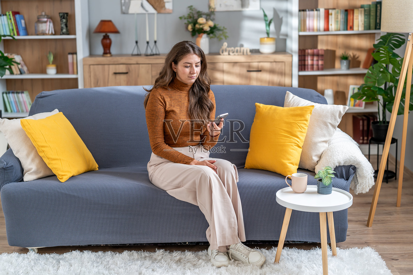 年轻女子在家中放松地坐在沙发上使用智能手机照片摄影图片