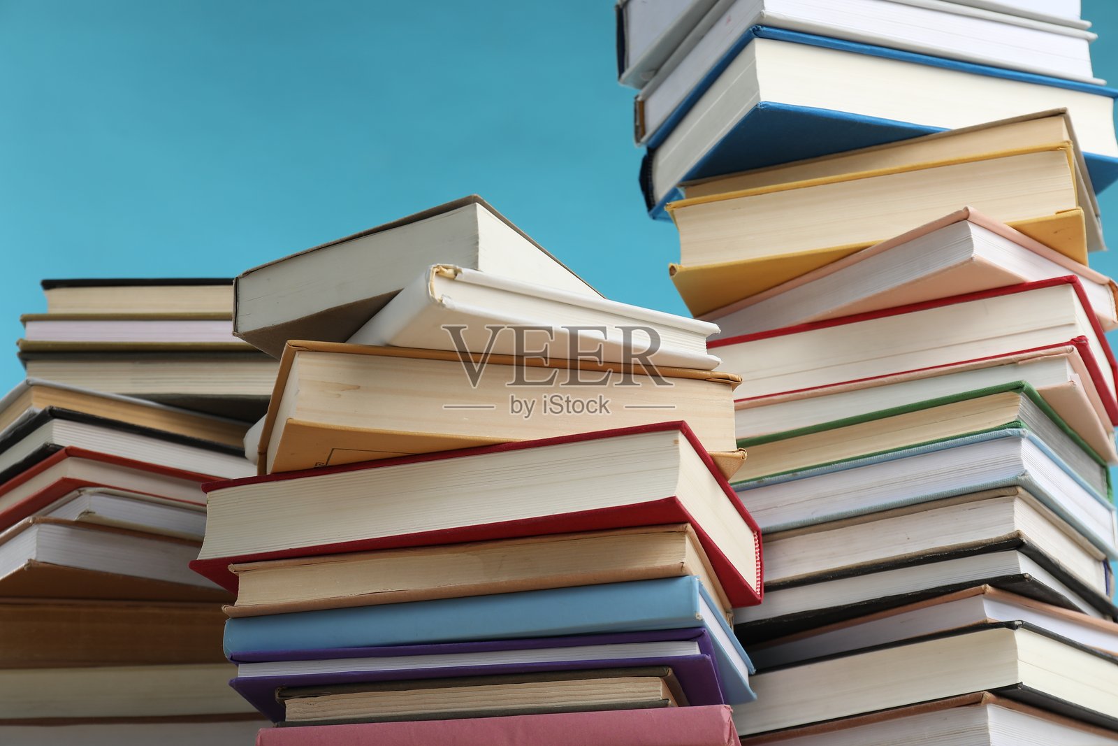 浅蓝色背景下堆叠的许多书籍,特写照片摄影图片