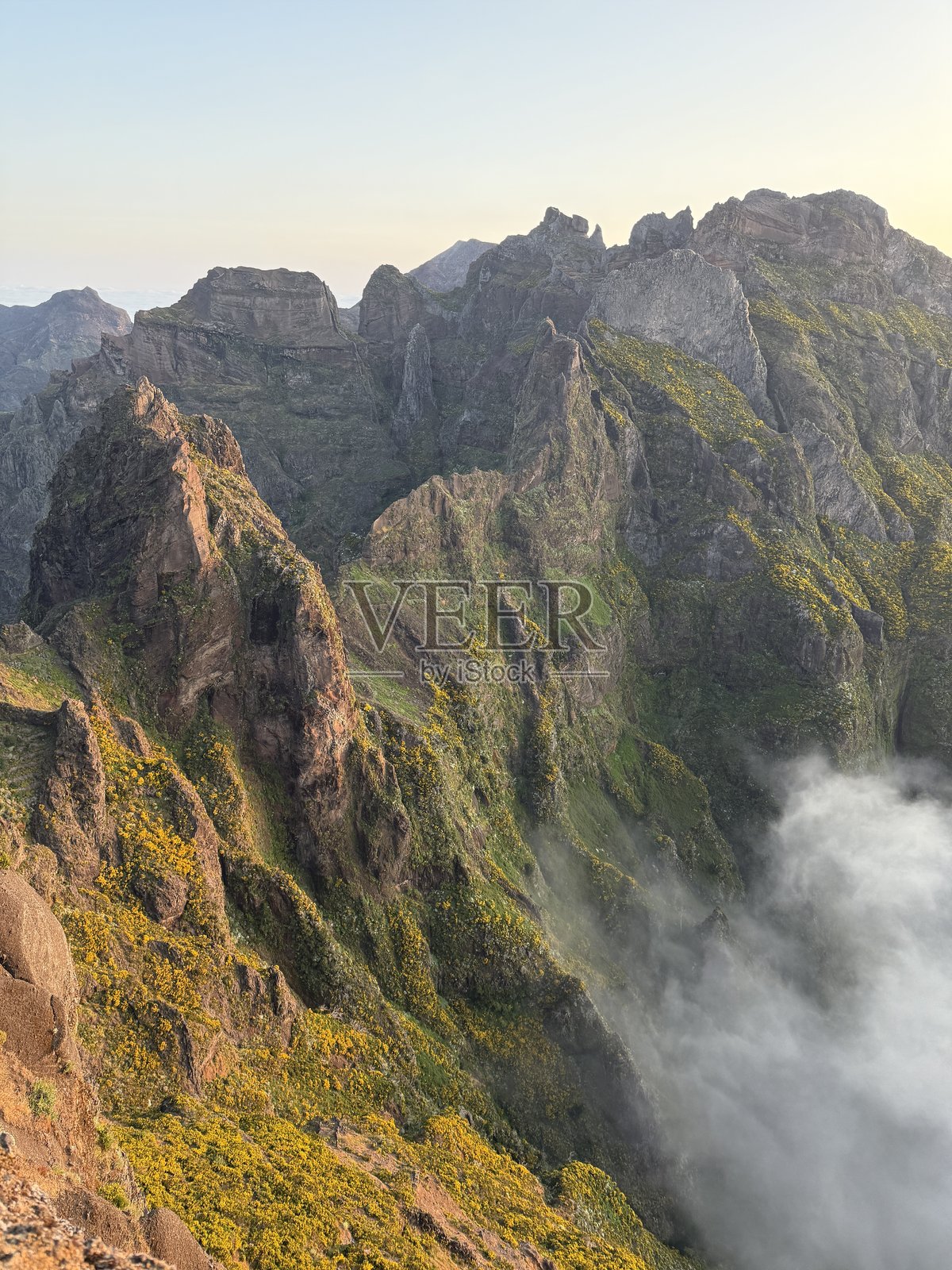 葡萄牙马德拉岛,皮科·杜·阿里埃罗山脉在云端之上,沐浴在温暖的日出阳光下照片摄影图片
