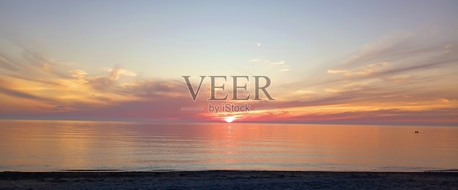 从加拿大一侧看到的休伦湖上空绚丽的日落,预示着明天将是美好的一天。三个年轻人正在靠近岸边的水中享受着宁静的夏日傍晚。海滩现在几乎空无一人,但明天又会热闹起来。照片摄影图片