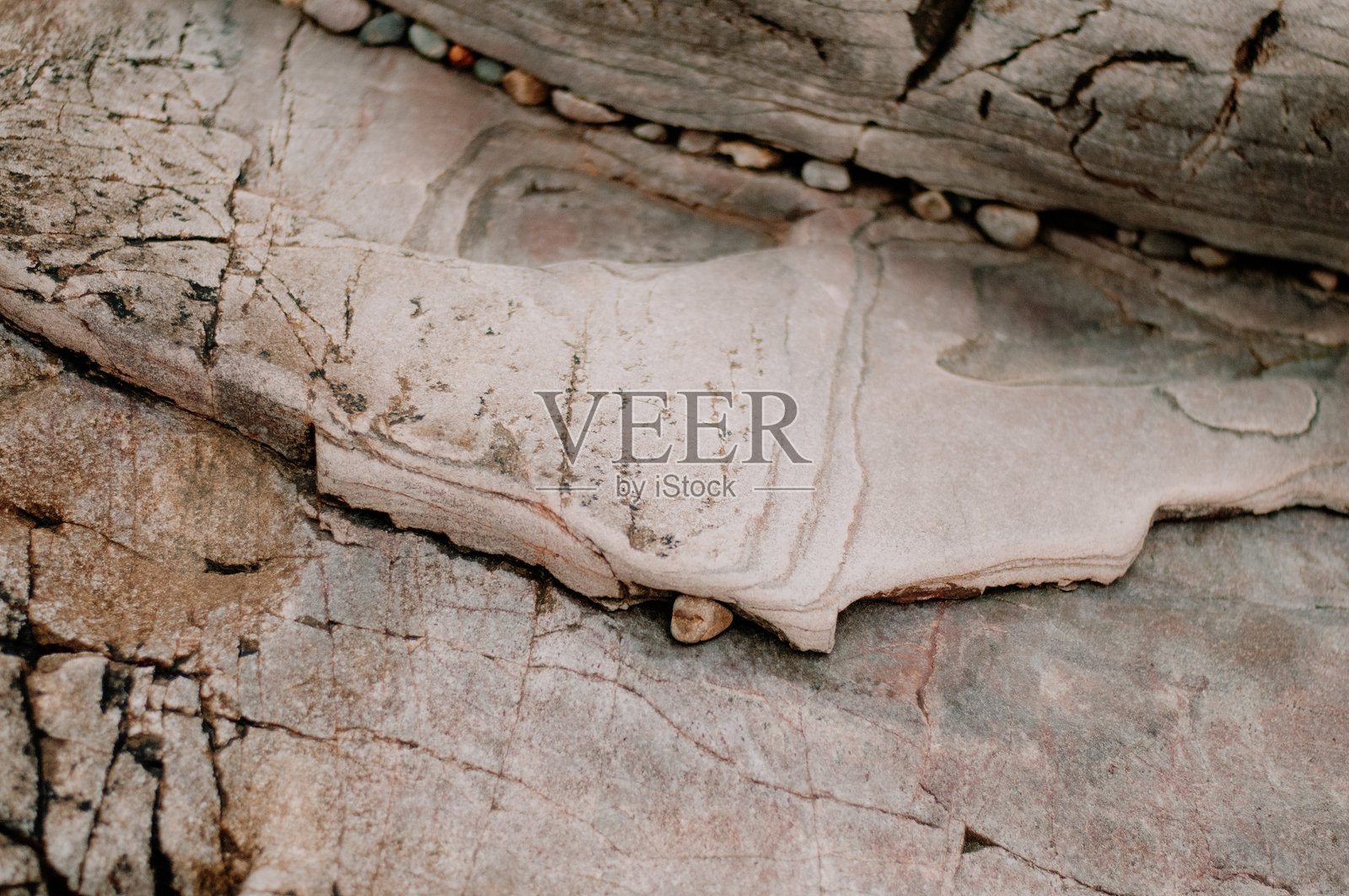 带有裂缝和嵌入卵石的层状岩石构造特写照片摄影图片