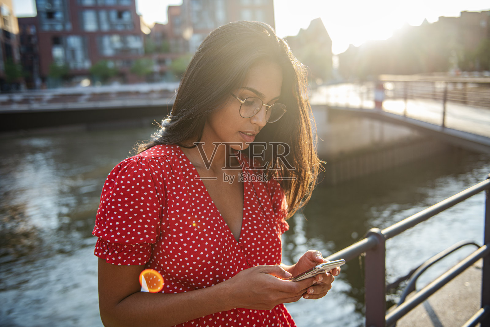 日落时分,年轻女子在河边使用智能手机照片摄影图片