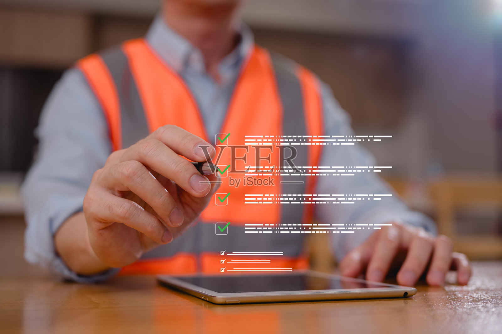 身穿安全背心的工程师在建筑工地上操作平板电脑,屏幕上显示着虚拟核对清单。该工程师正在检查项目,涉及安全装备、项目管理、质量控制和合规性审查。照片摄影图片