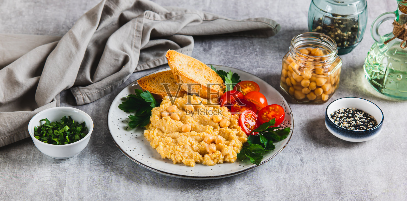鹰嘴豆泥、番茄、吐司和蔬菜摆放在餐桌上的盘子里,作为网络横幅照片摄影图片