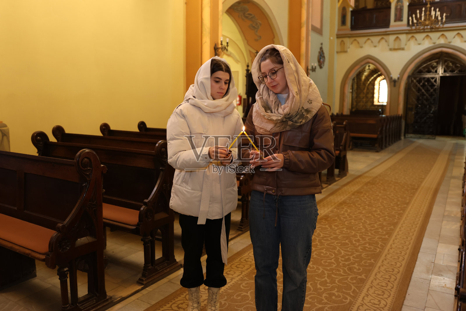 两位女士在教堂点燃蜡烛,专注于祈祷和精神时刻照片摄影图片