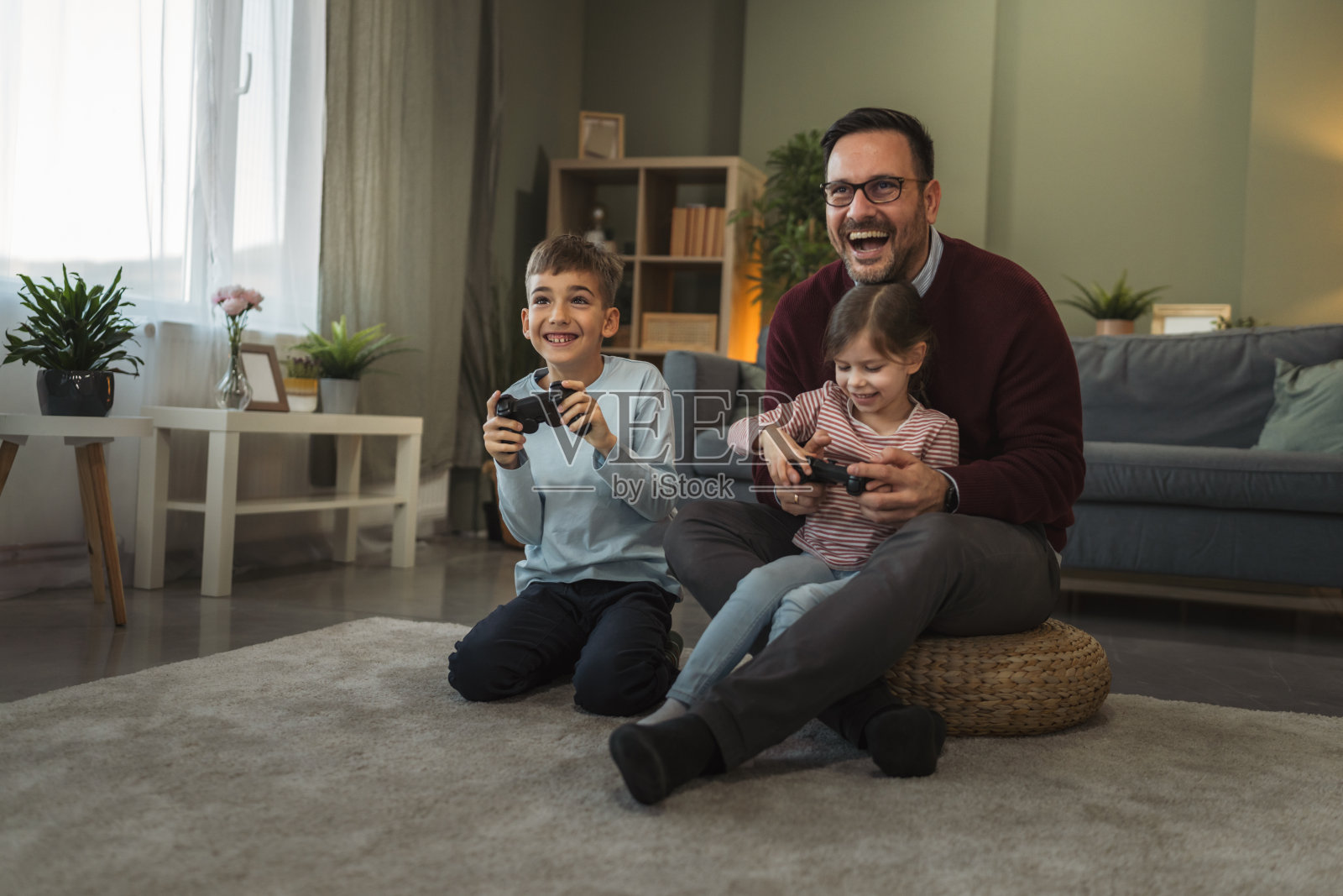 父亲和孩子们在家玩电子游戏,开怀大笑照片摄影图片