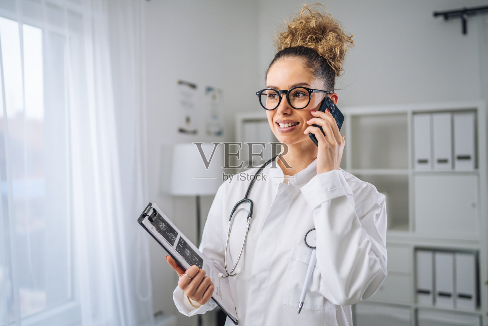 女医生在办公室里微笑着打电话照片摄影图片