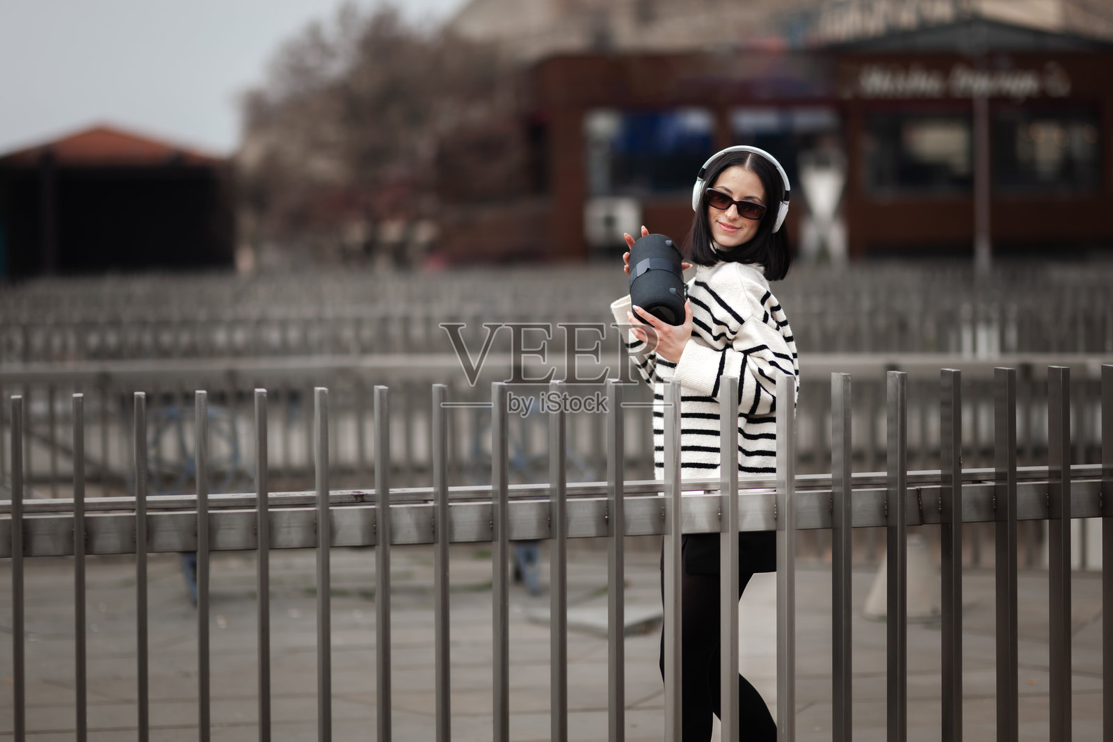 一个女孩在阳光明媚的白天,在一个充满活力的户外场所,享受音乐并快乐地跳舞,展现她对节奏和律动的热情,周围气氛活跃照片摄影图片