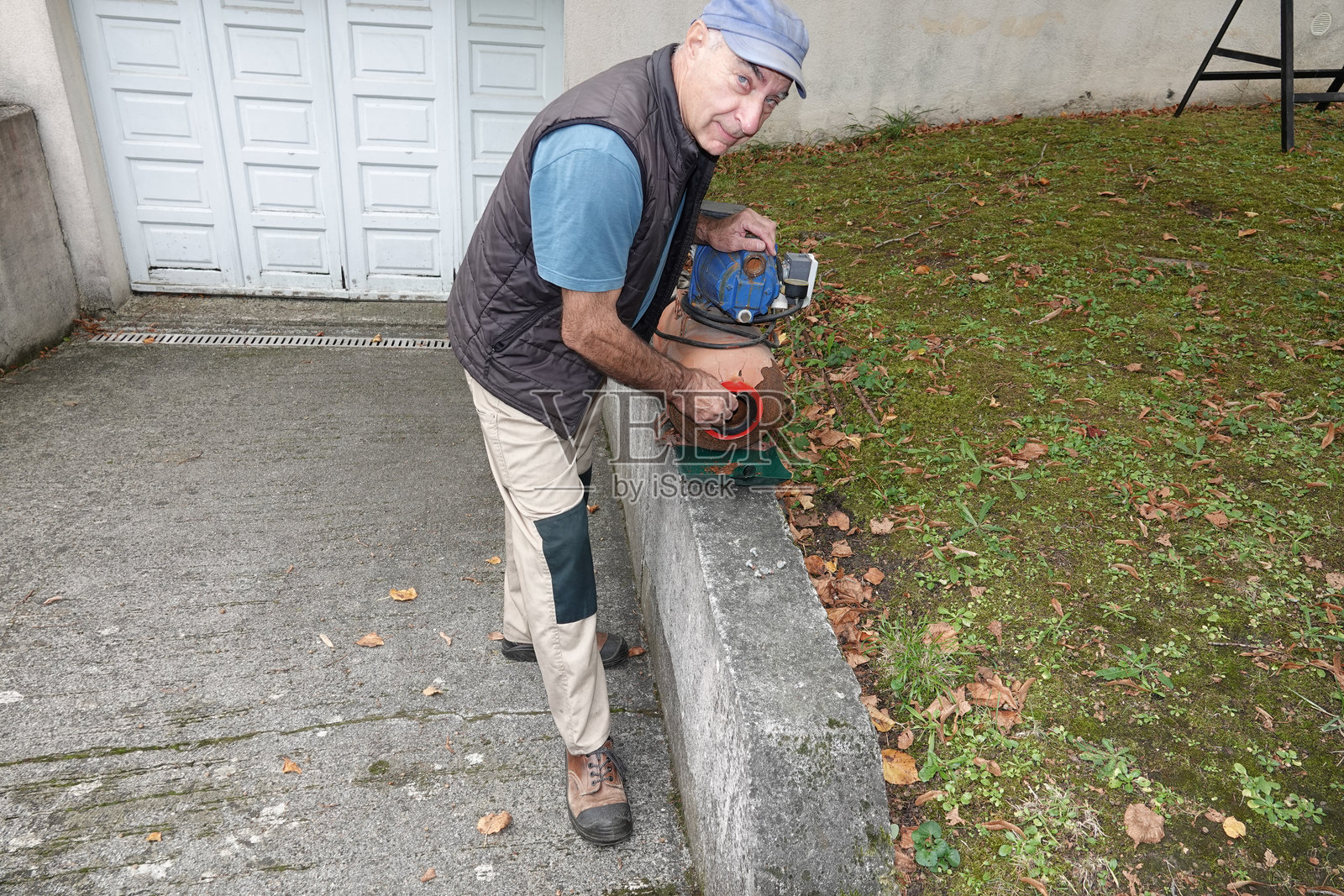 男人在户外用工具修理设备,设备靠近墙壁照片摄影图片
