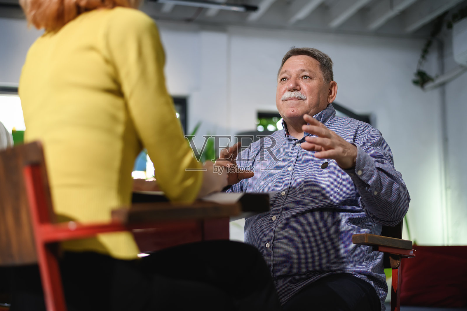 白天,在现代办公室里,一位商务人士正在与同事进行商务讨论。照片摄影图片