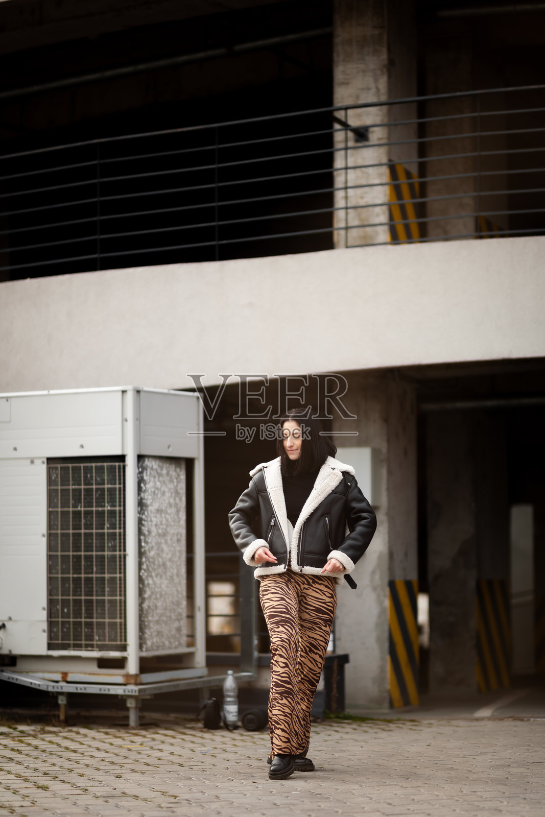 一位身着时尚服装、印有大胆图案的女孩在午后时分于城市环境中翩翩起舞,在现代化的背景下展现出流畅的舞姿和活泼的精神。照片摄影图片