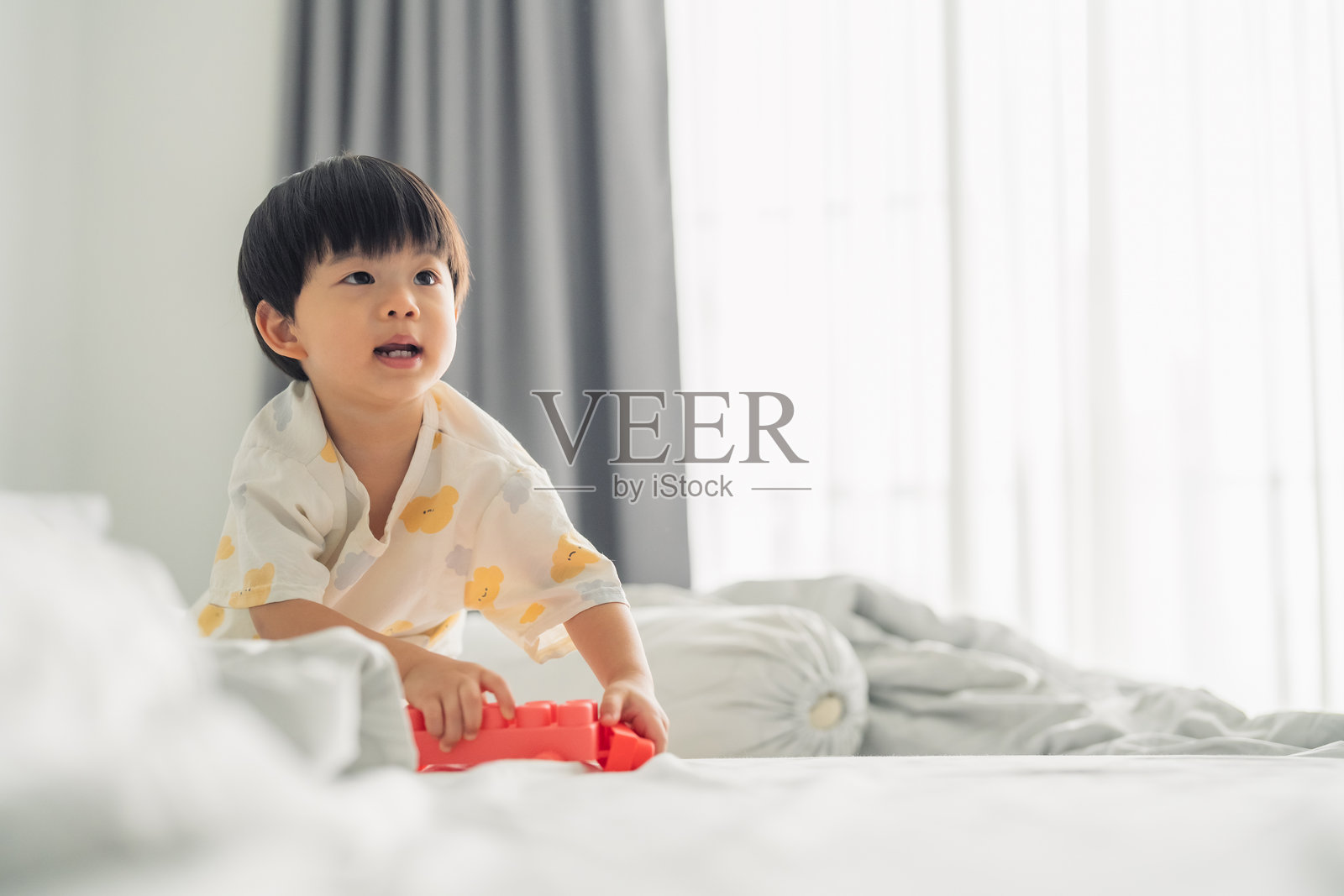 一个令人愉快的亚洲幼儿,两到三岁,刚睡醒,穿着睡衣,在充满童趣、天真和纯粹兴奋的温馨放松的家庭氛围中,开心地笑着、跳着、跑着玩耍,充满好奇心。照片摄影图片