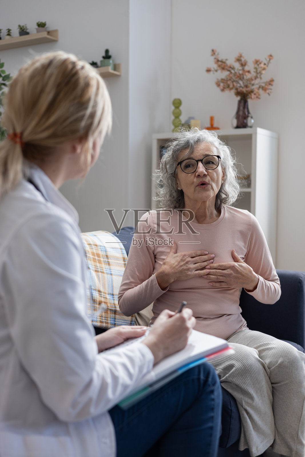 一位年长女性向居家护理护士描述胸痛照片摄影图片