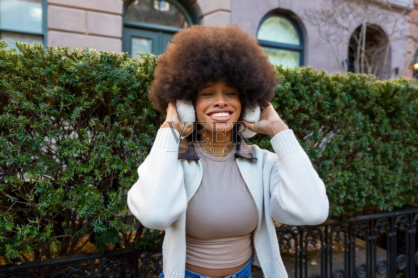 一位年轻的非裔美国女性戴着耳罩,面带微笑,背景是纽约市。照片摄影图片