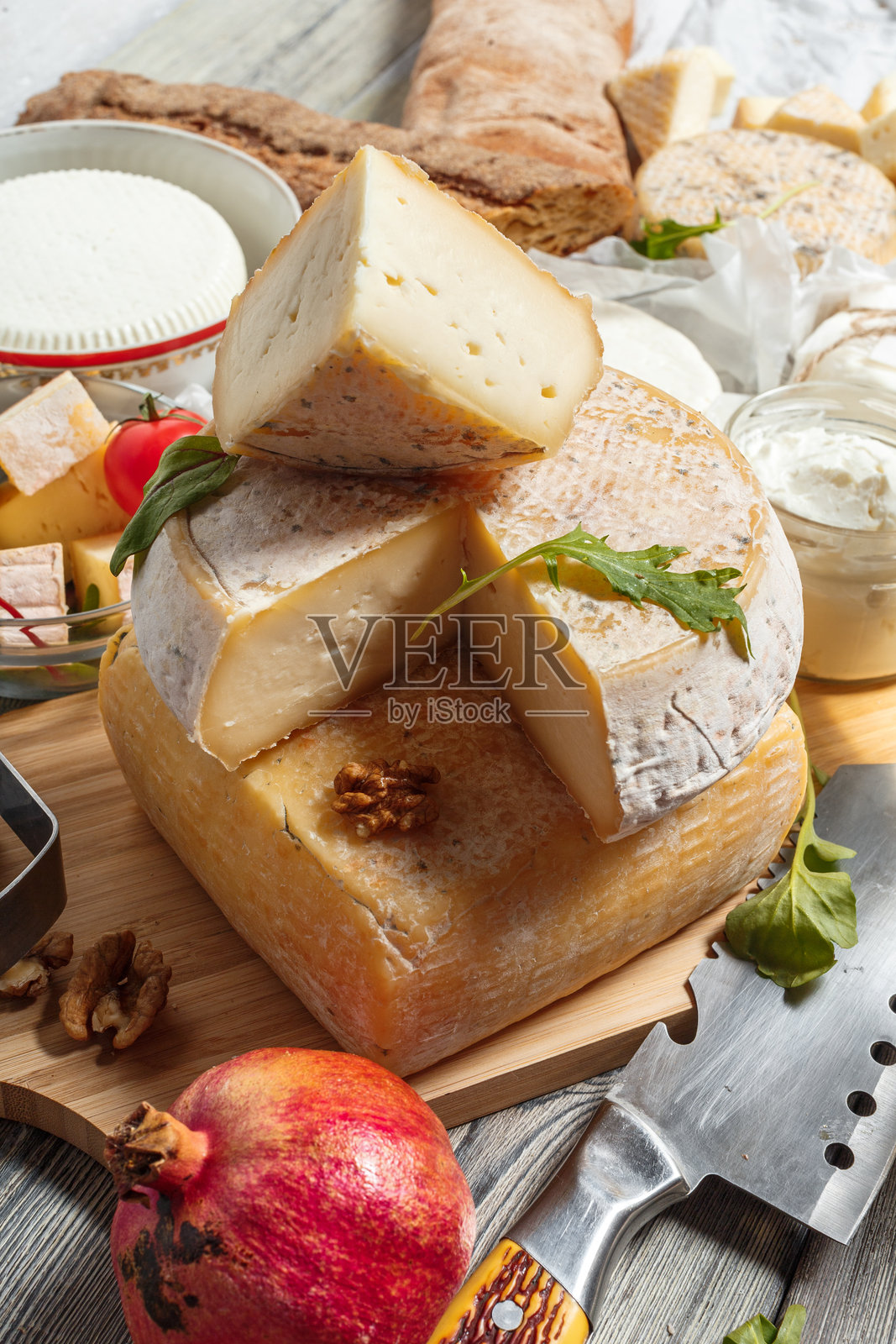 乡村风格的桌子上摆放着奶酪拼盘,包含多种奶酪和新鲜食材照片摄影图片