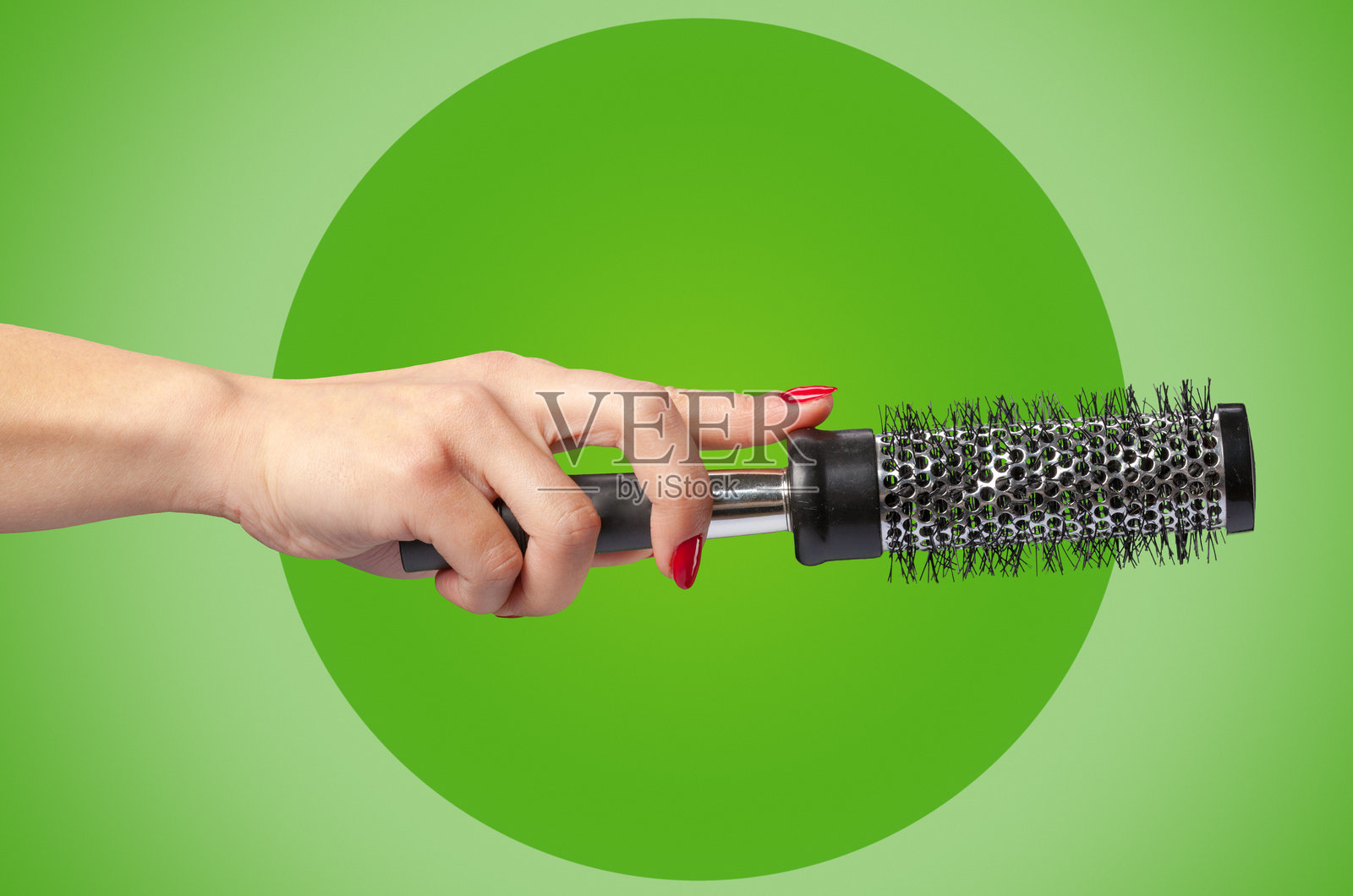 一只手拿着圆筒形发梳,背景是鲜艳的绿色照片摄影图片