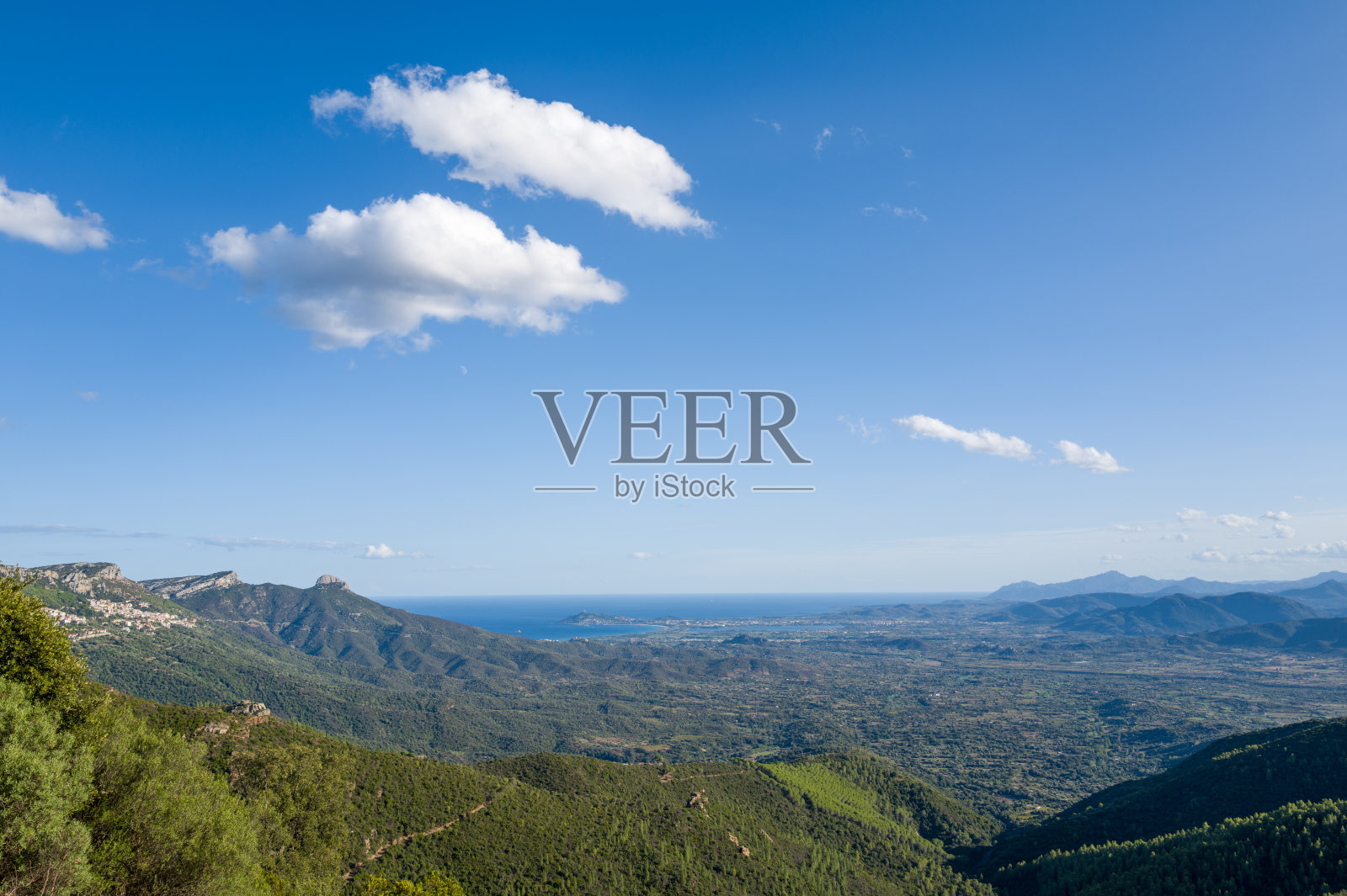 广阔的绿色山丘延伸至蔚蓝大海的景观照片摄影图片