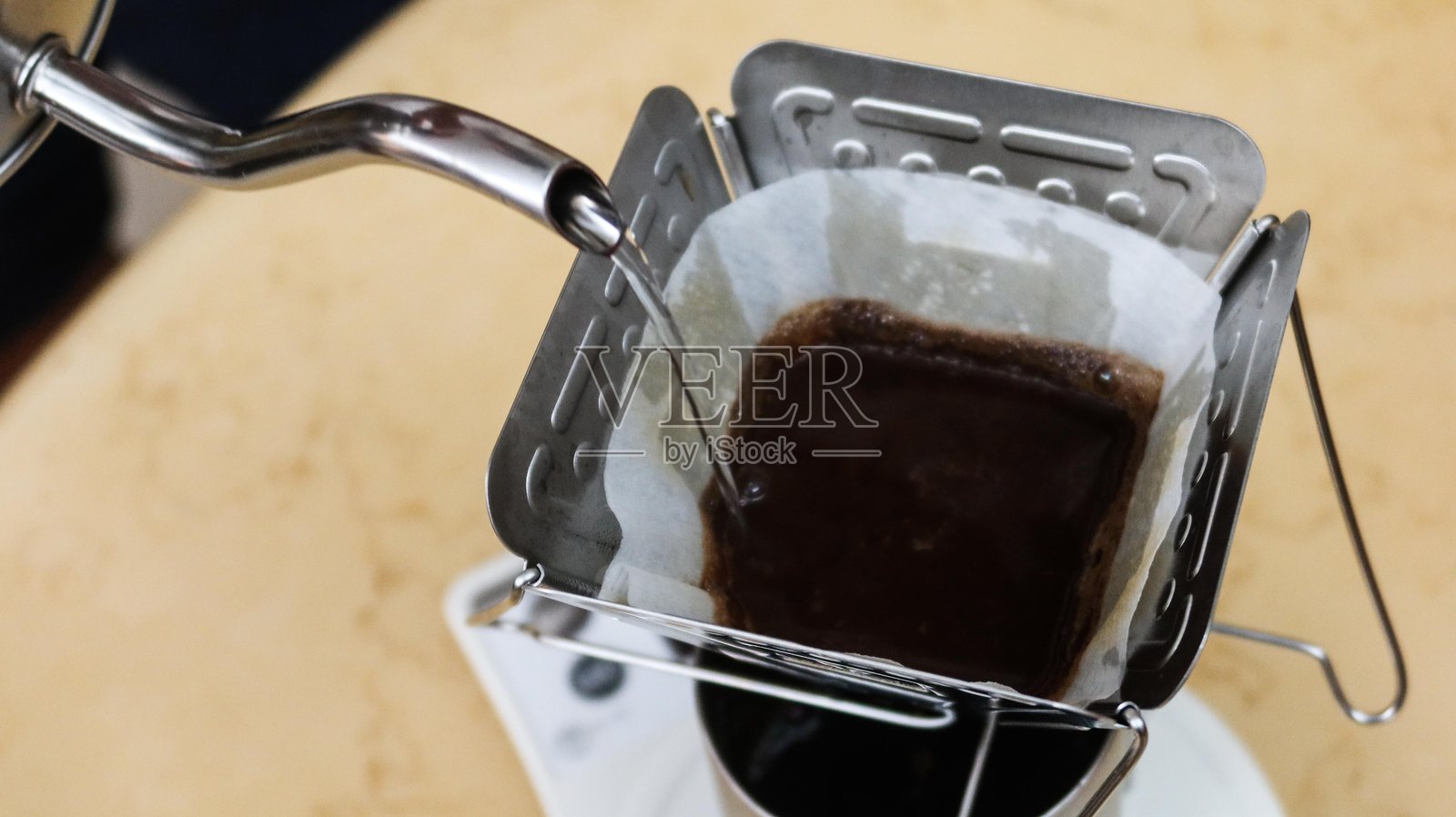 用手冲壶向研磨好的咖啡粉中加入热水照片摄影图片