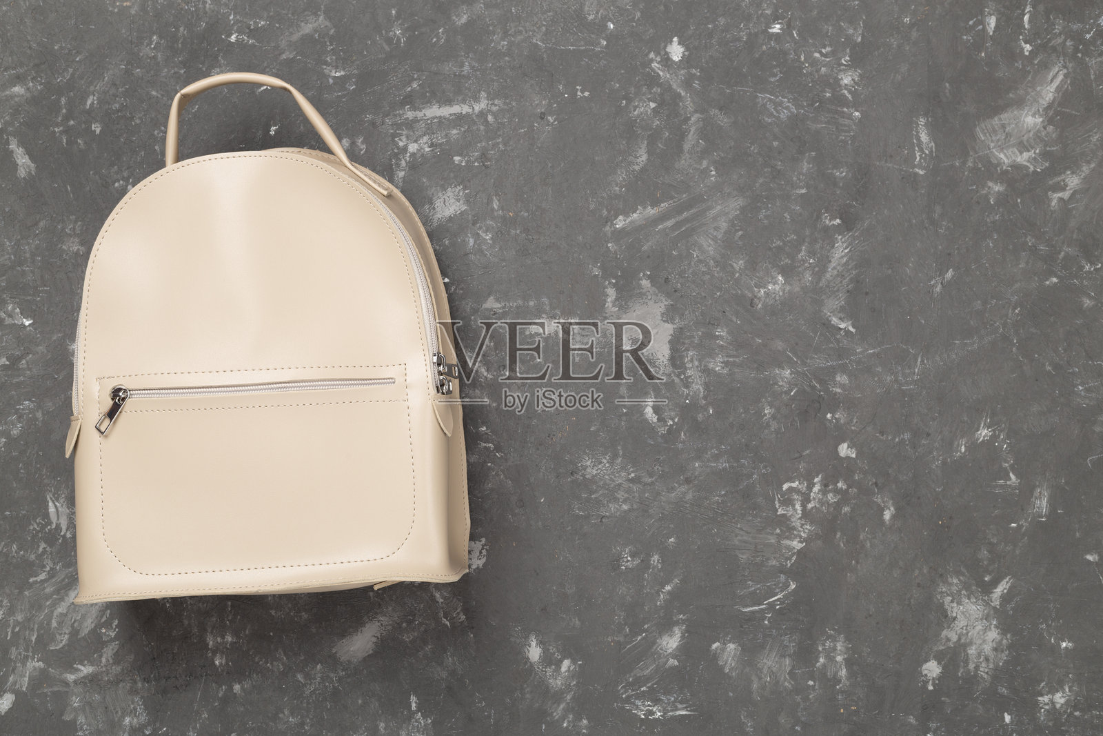 女性时尚米色背包,水泥背景,俯视照片摄影图片