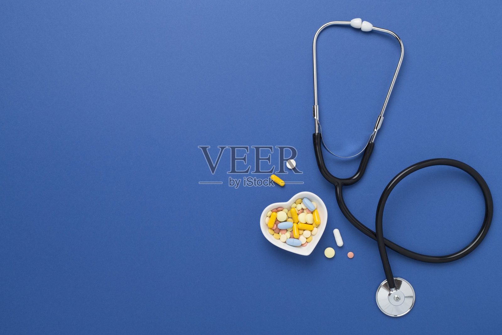 听诊器与心脏药物,彩色背景,俯视照片摄影图片