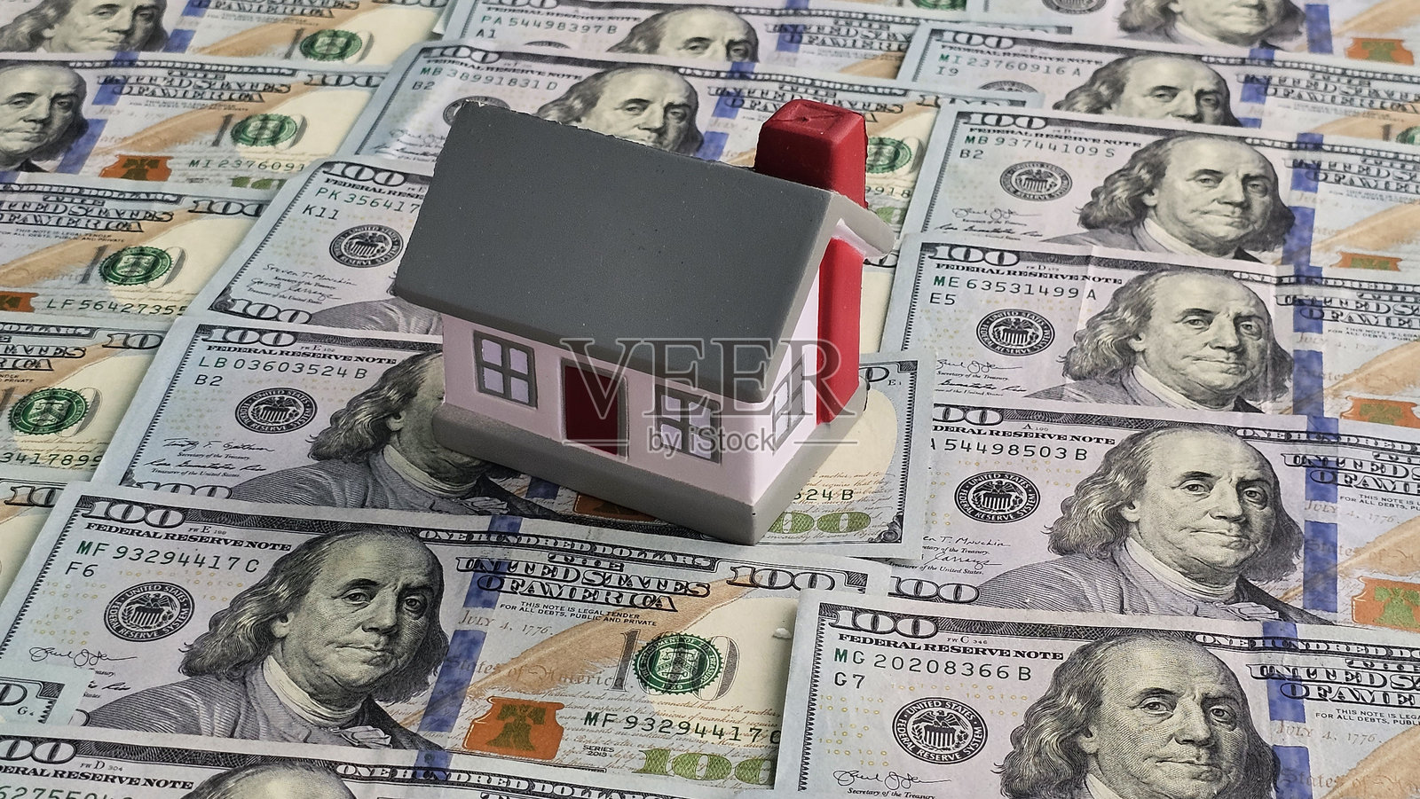 模型房屋坐落在百元美钞上,着重于房地产和金融照片摄影图片