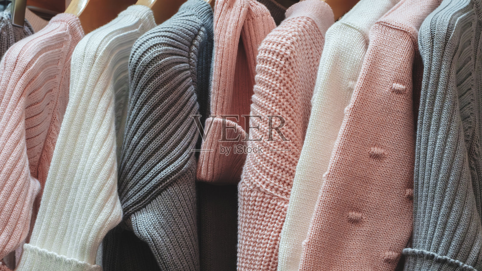 一排色彩各异的毛衣,包括粉色和白色,正挂在晾衣绳上照片摄影图片