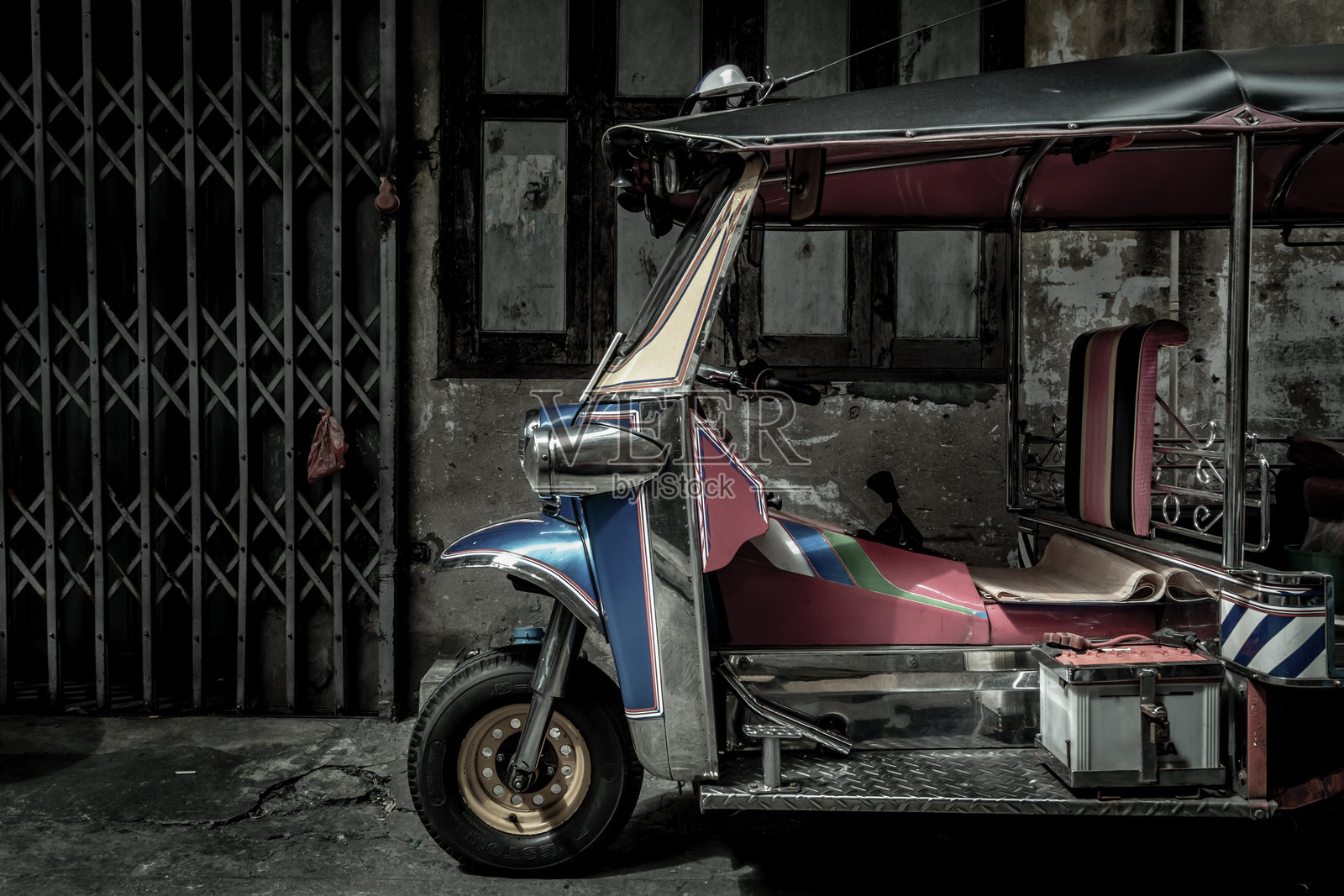 著名的蓝色嘟嘟车,泰国传统出租车的前部,背景是一面古老的墙。照片摄影图片