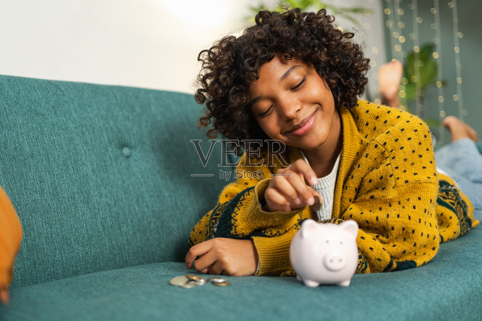 非洲裔美国女孩将硬币存入粉色储蓄罐,为未来储蓄投资。储蓄、投资、预算、商业、财富、退休、金融、金钱、银行概念。照片摄影图片