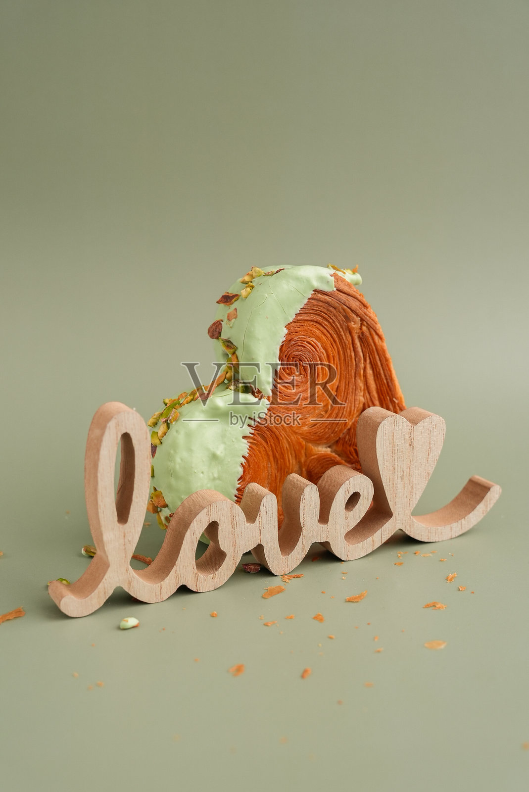 木质的爱心单词,情人节假日,绿底 Pistachio 可颂,留有复制空间。酥皮潮流甜点烘焙。奶油面团实验。照片摄影图片