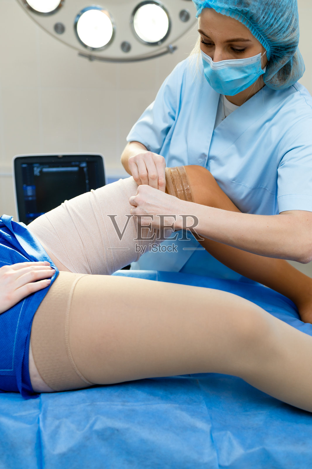 静脉治疗手术后穿着弹力袜。医生在血管手术后帮助患者穿上弹力袜。照片摄影图片