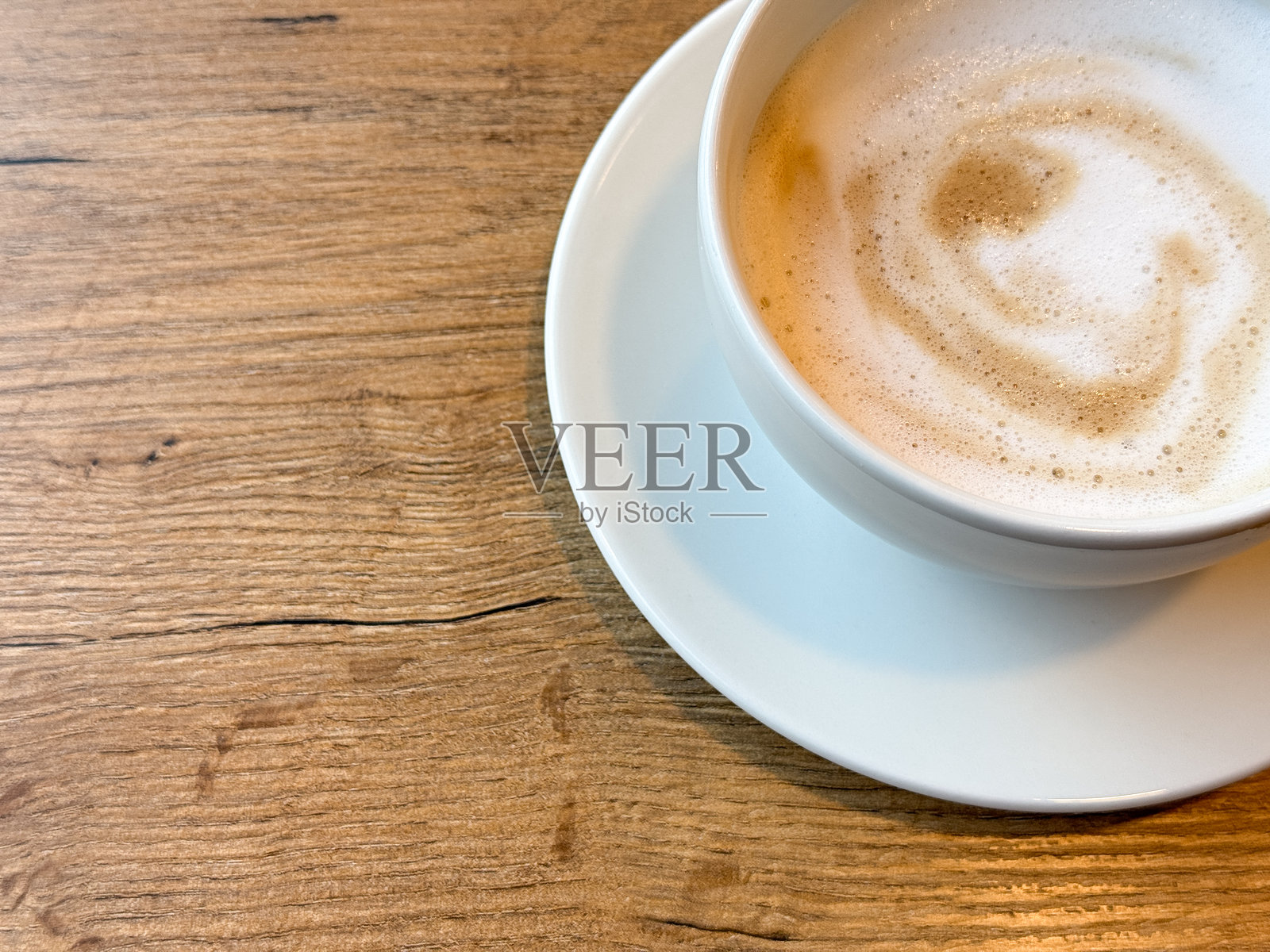 俯视角度拍摄的白色咖啡杯和碟子,摆放在咖啡馆的桌子上。极简静物构图,表达咖啡馆生活方式、简约、晨间例行和放松的概念。照片摄影图片