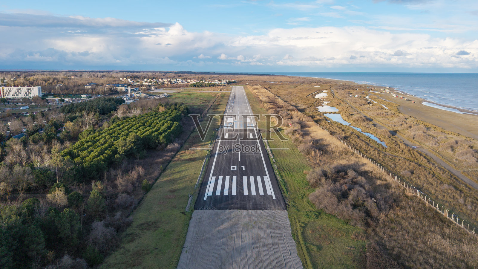 晴朗天气下,飞机跑道延伸至大海的航拍景象照片摄影图片