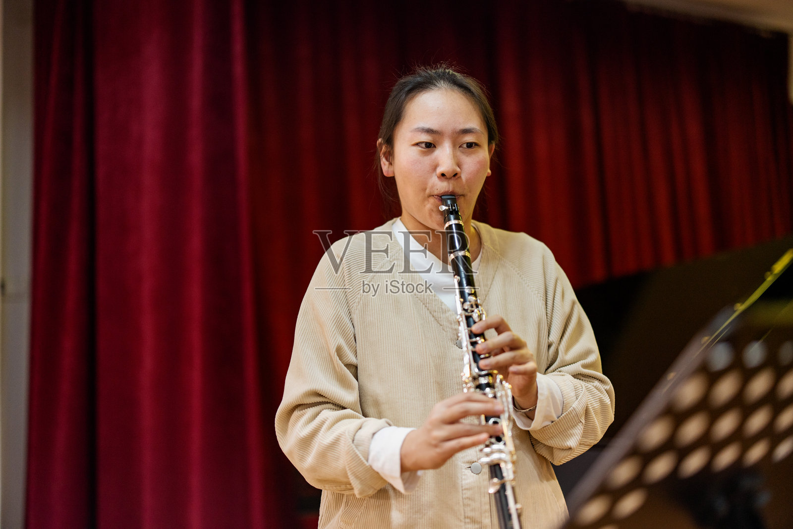 亚洲学生在小型音乐会舞台上学习演奏单簧管照片摄影图片