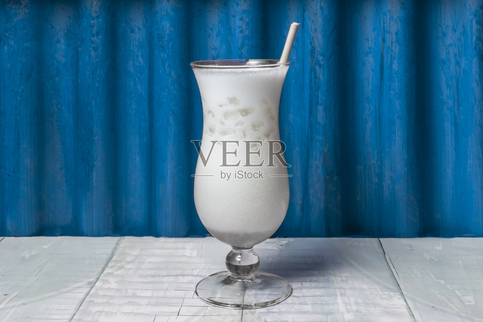 白色桌子上的插有吸管的菠萝椰子酒照片摄影图片