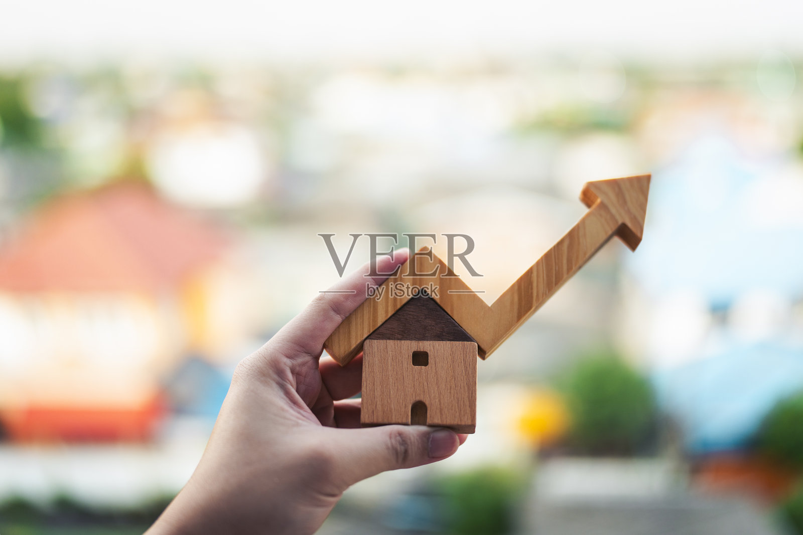 手握着一栋木屋,旁边有一个向上的箭头,象征着房地产增长、房产投资、房价上涨、住房市场趋势、财务成功和长期财富规划的概念。照片摄影图片