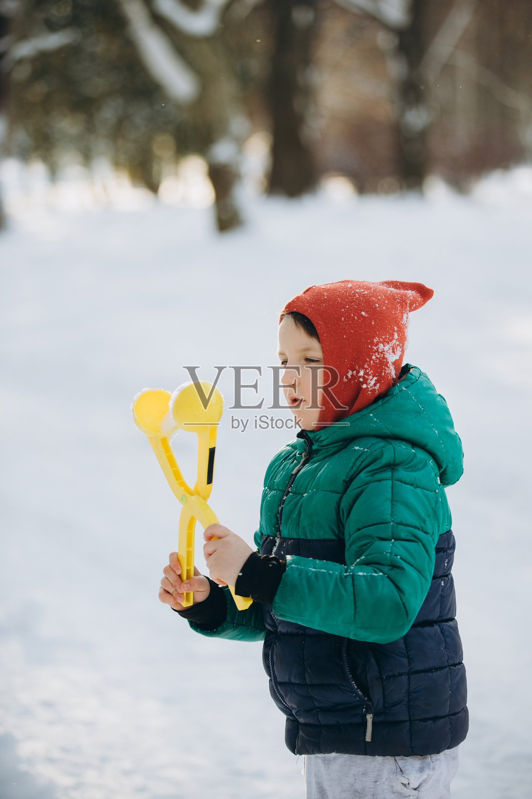 男孩在冬日公园里玩雪球制造器照片摄影图片