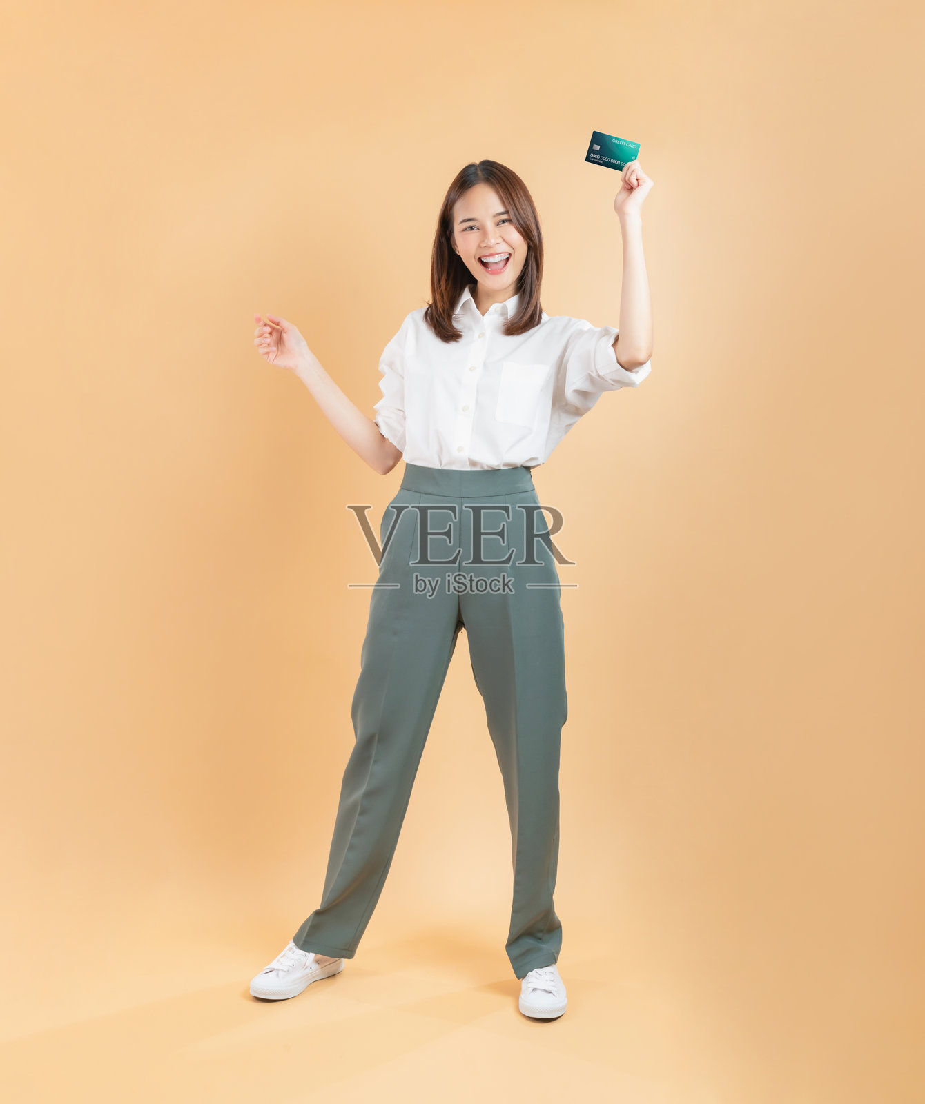 一位快乐的年轻女子在庆祝成功购物时,手中拿着信用卡。照片摄影图片