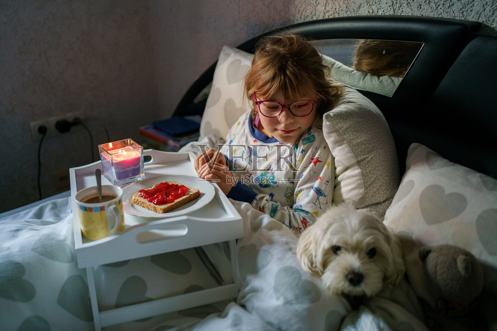 小女孩在床上吃早餐。可爱的小马尔济斯犬和孩子在一起。照片摄影图片
