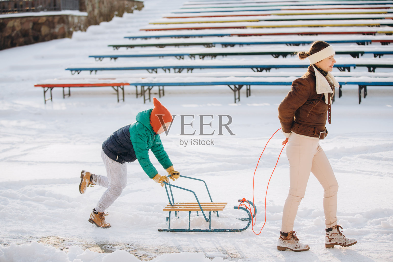 一位母亲和她的儿子在冬天的公园里玩雪橇照片摄影图片