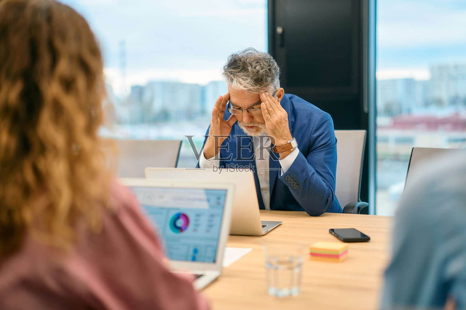 一位年长的商人开会时感到压力和头痛照片摄影图片