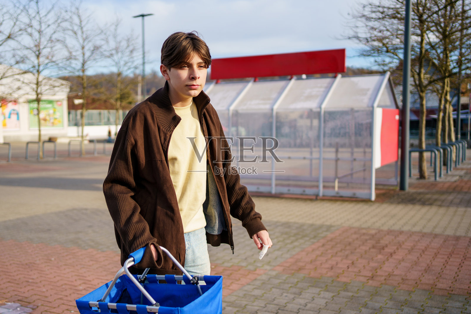 青少年男孩在去超市购物的路上,搬运着一箱瓶装水饮料。照片摄影图片
